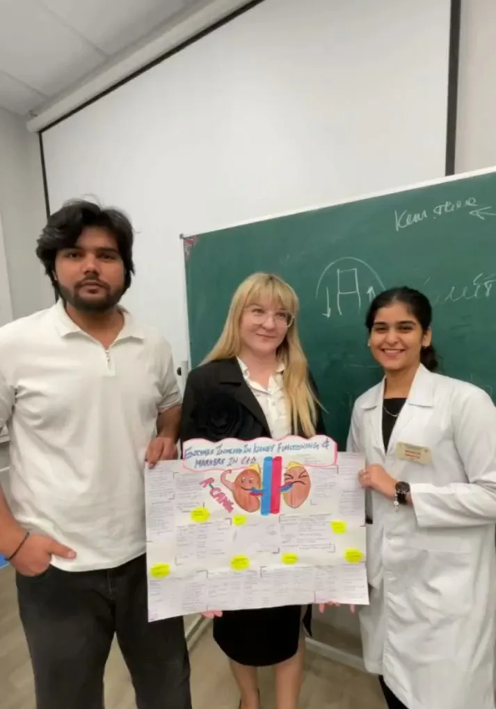Three people holding a kidney-related educational poster in front of a chalkboard