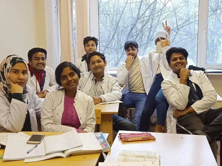 Medical students in white coats sitting together in a classroom