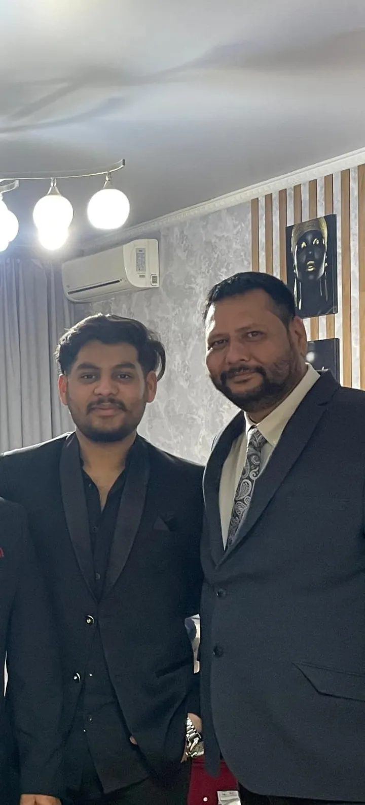 Two people in formal suits posing together indoors