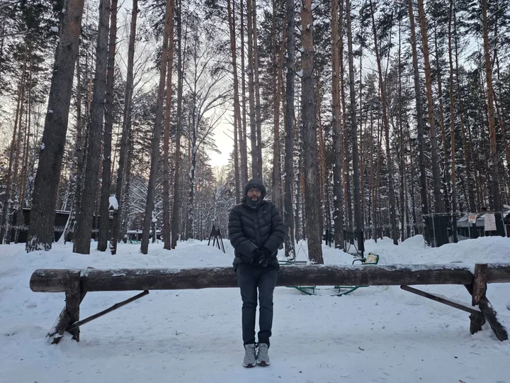 A person in winter clothing standing in a snow-covered wooded area
